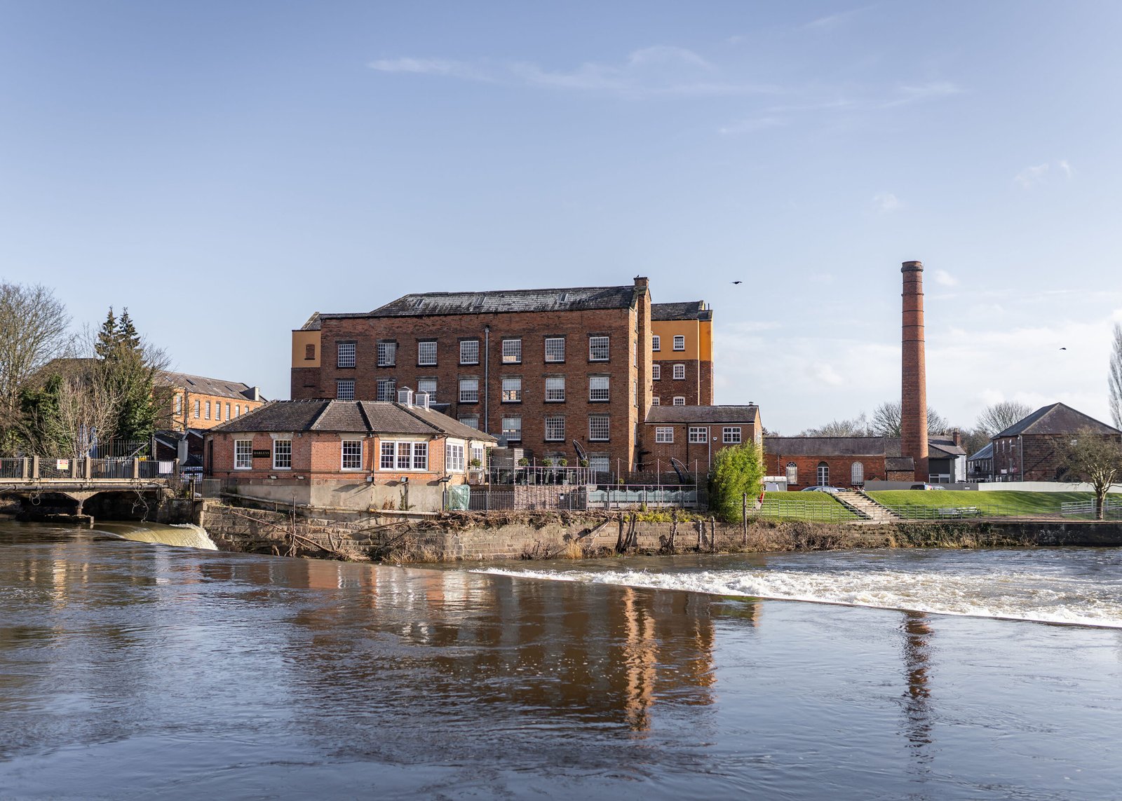 Mill on the river Derwent at Derby Abby. Mill on the river Derwent at Derby Abby. Fast flowing beautiful river and old mill warehouse with red brick chimney.